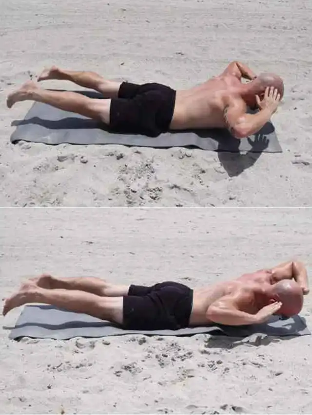 a man lying on a mat on sand