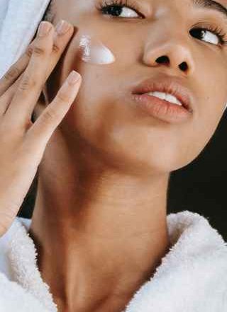 Woman looking at mirror while putting face cream on