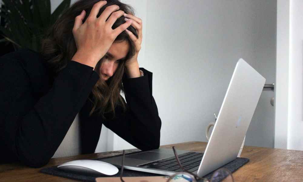 Women touching her head while looking at the computer