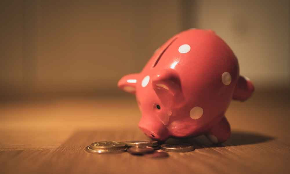 A piggy bank next to several metal coins.