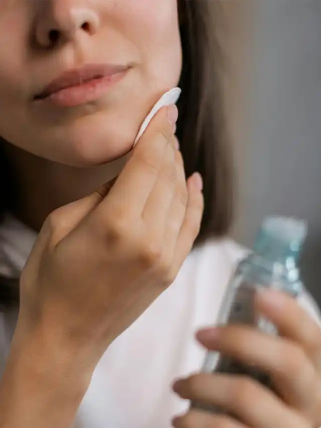 a woman using a cotton pad to remove her face