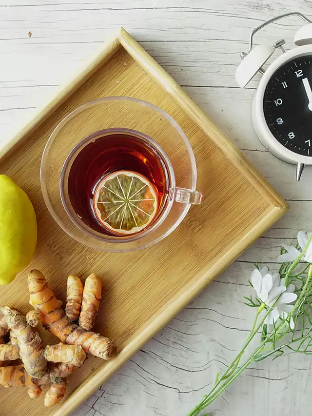 a cup of tea with lemon and ginger on a tray