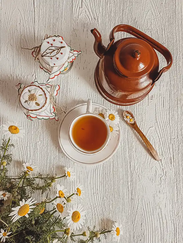 a tea cup and saucer with a teapot and flowers