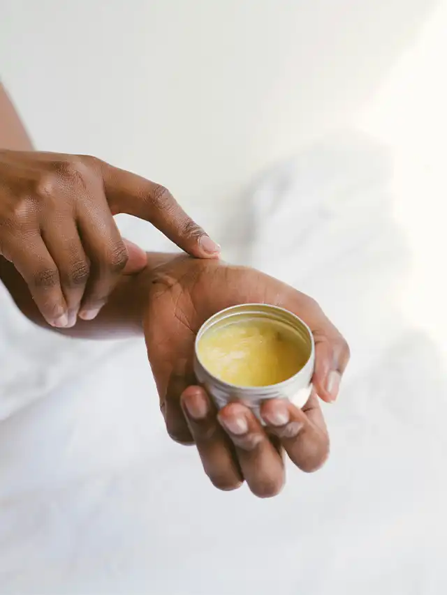 a person's hand holding a jar of cream