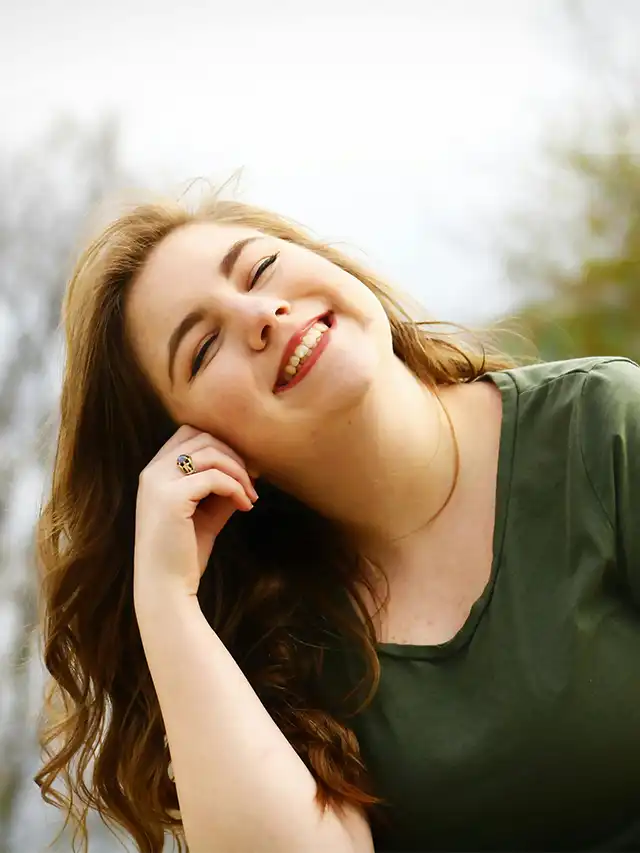 a woman smiling with her hand on her face