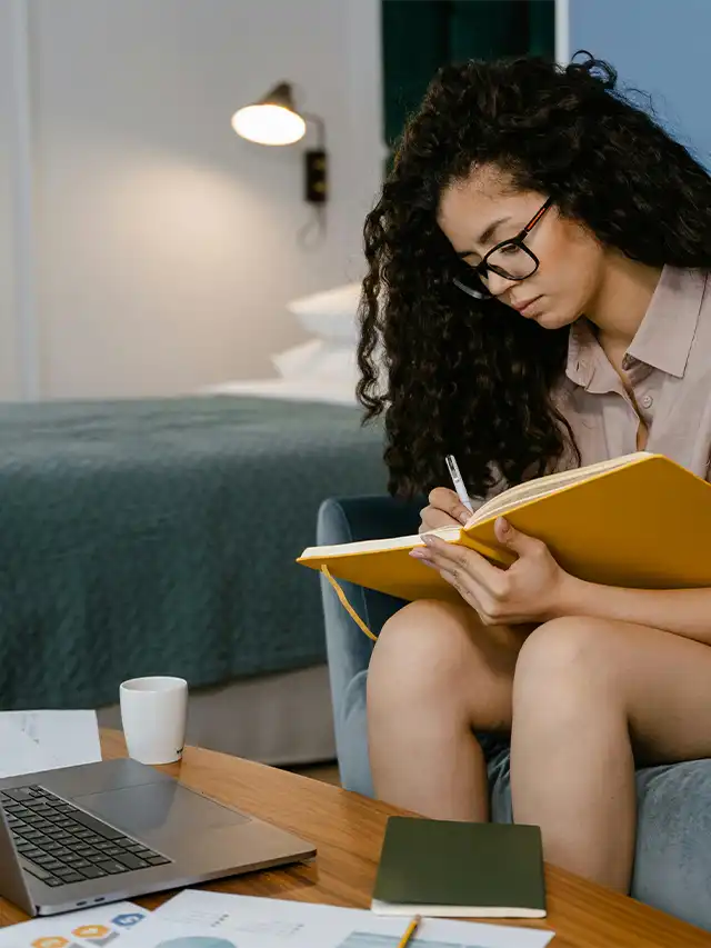 a woman sitting on a chair writing in a book